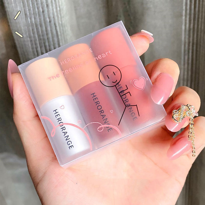 Set of lipsticks in a clear case held by a hand with pink nail polish.