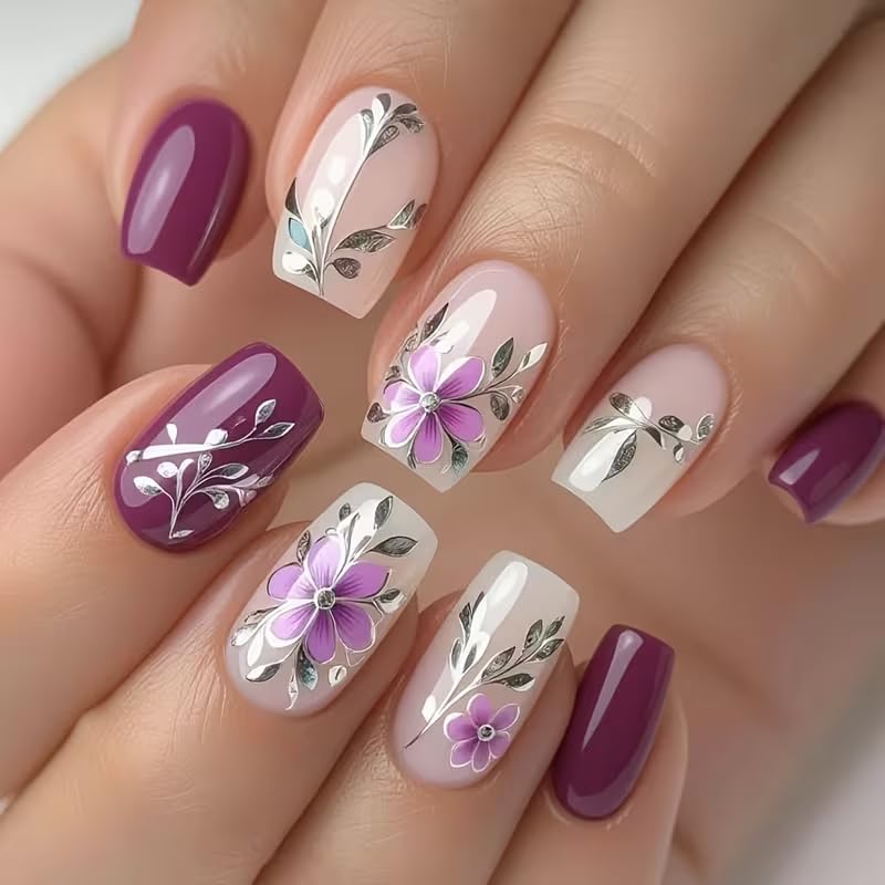 Nails with floral and leaf designs in purple, pink, and white on a neutral background