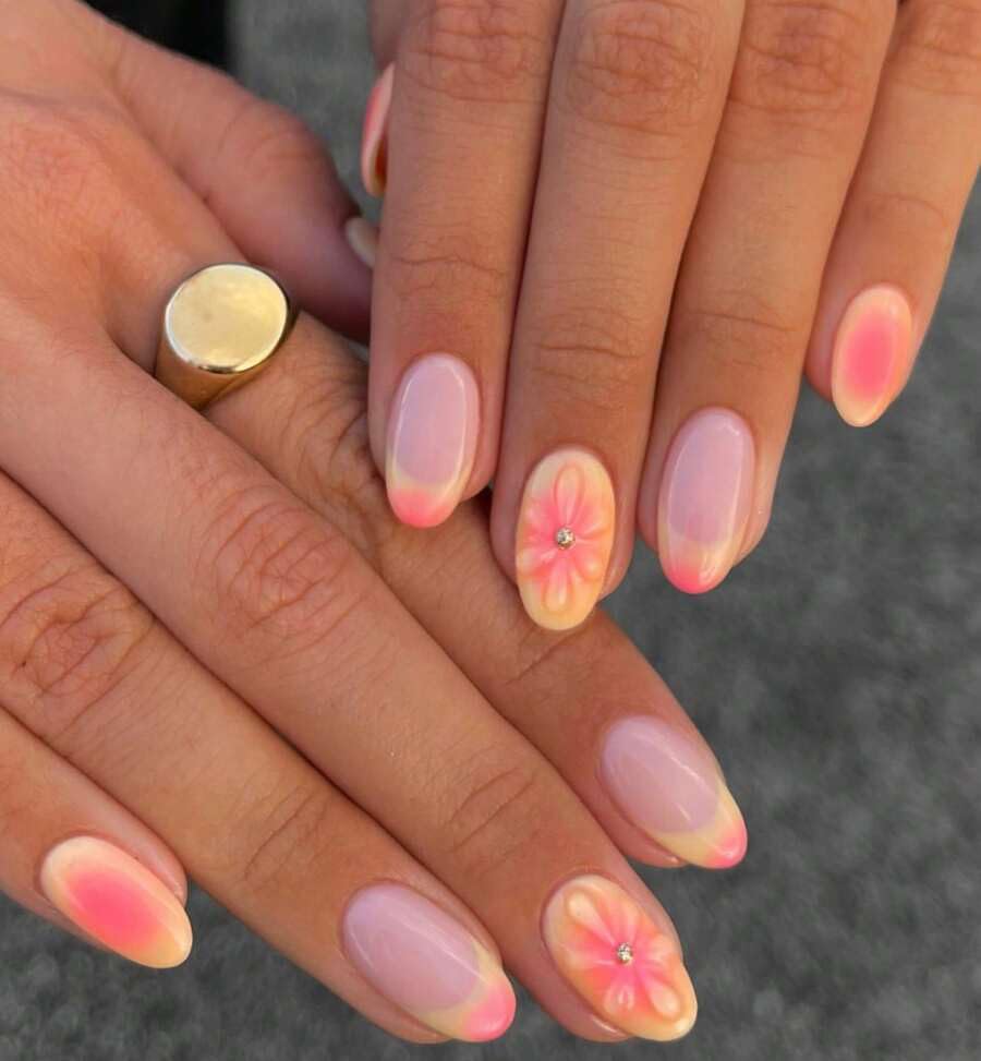 Close-up of hands with pink and orange floral nail art on a blurred background