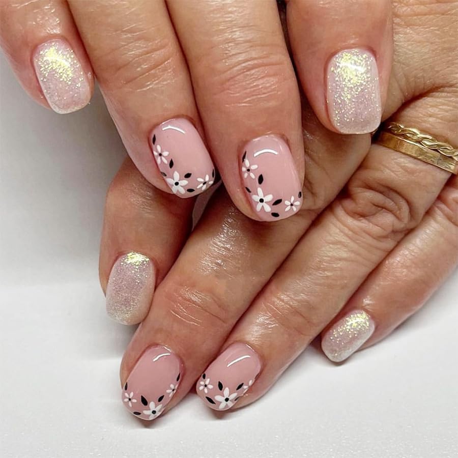 Close-up of hands with pink nail polish and floral designs on a white background