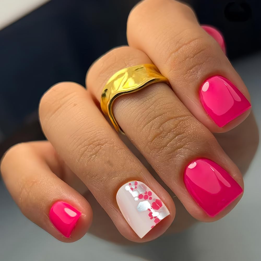 Hand with pink nail polish and a gold ring on a neutral background