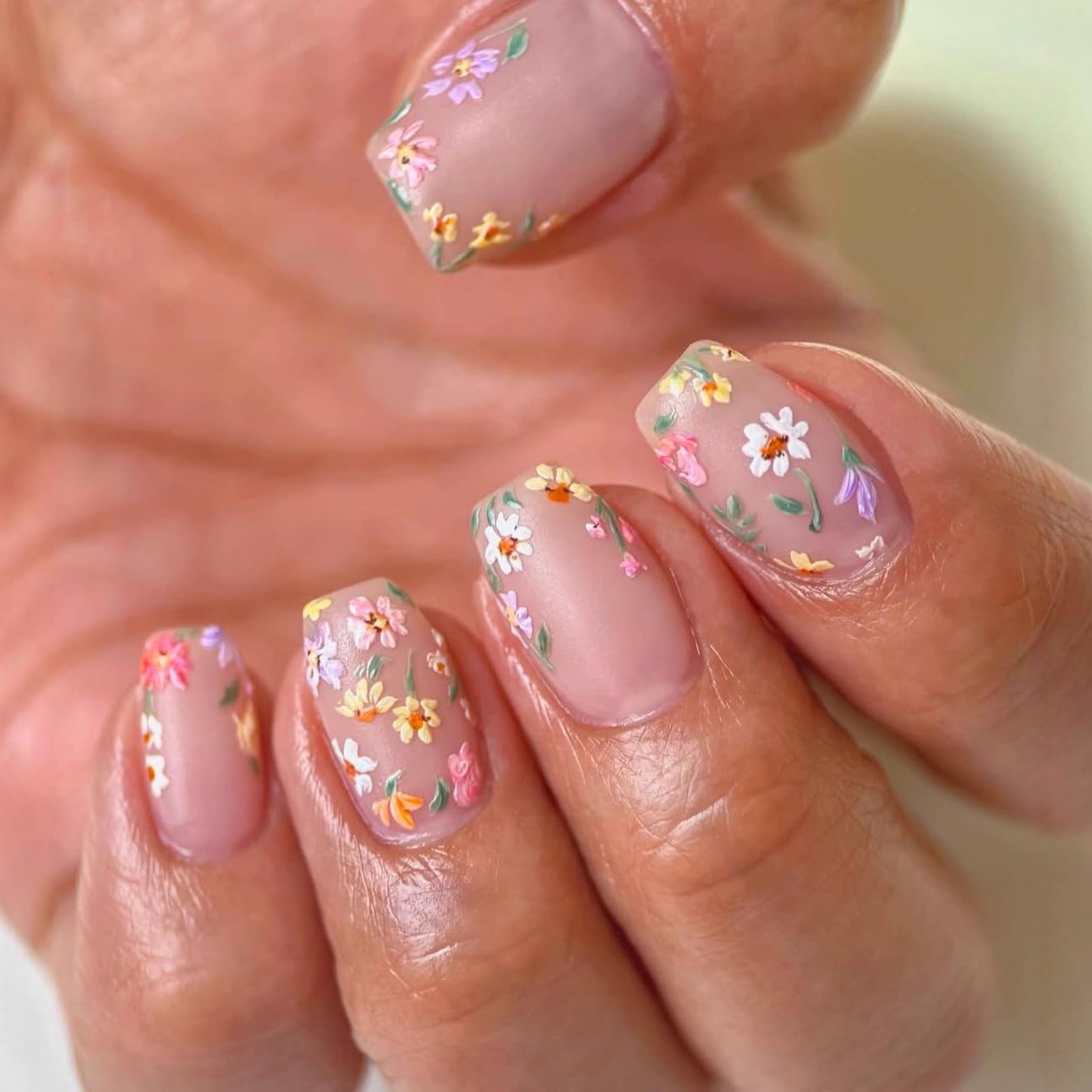 Nails with floral design held by a hand