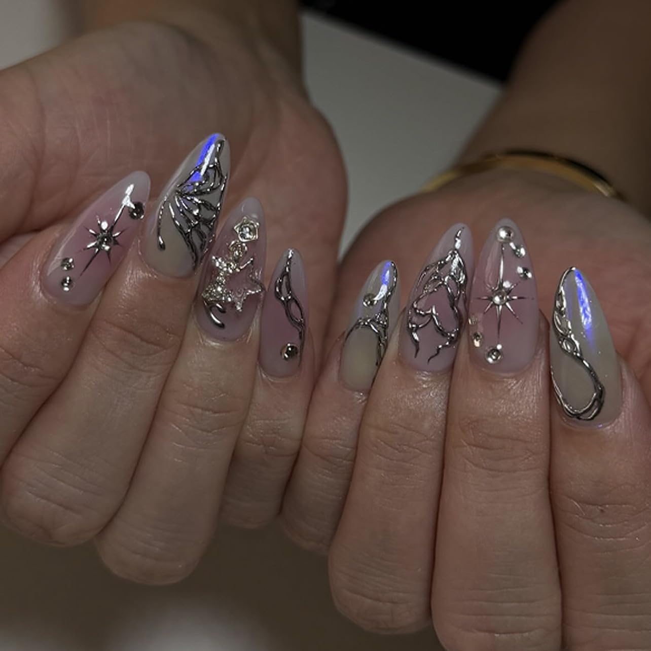 Close-up of hands with decorative nail art featuring silver and black designs.