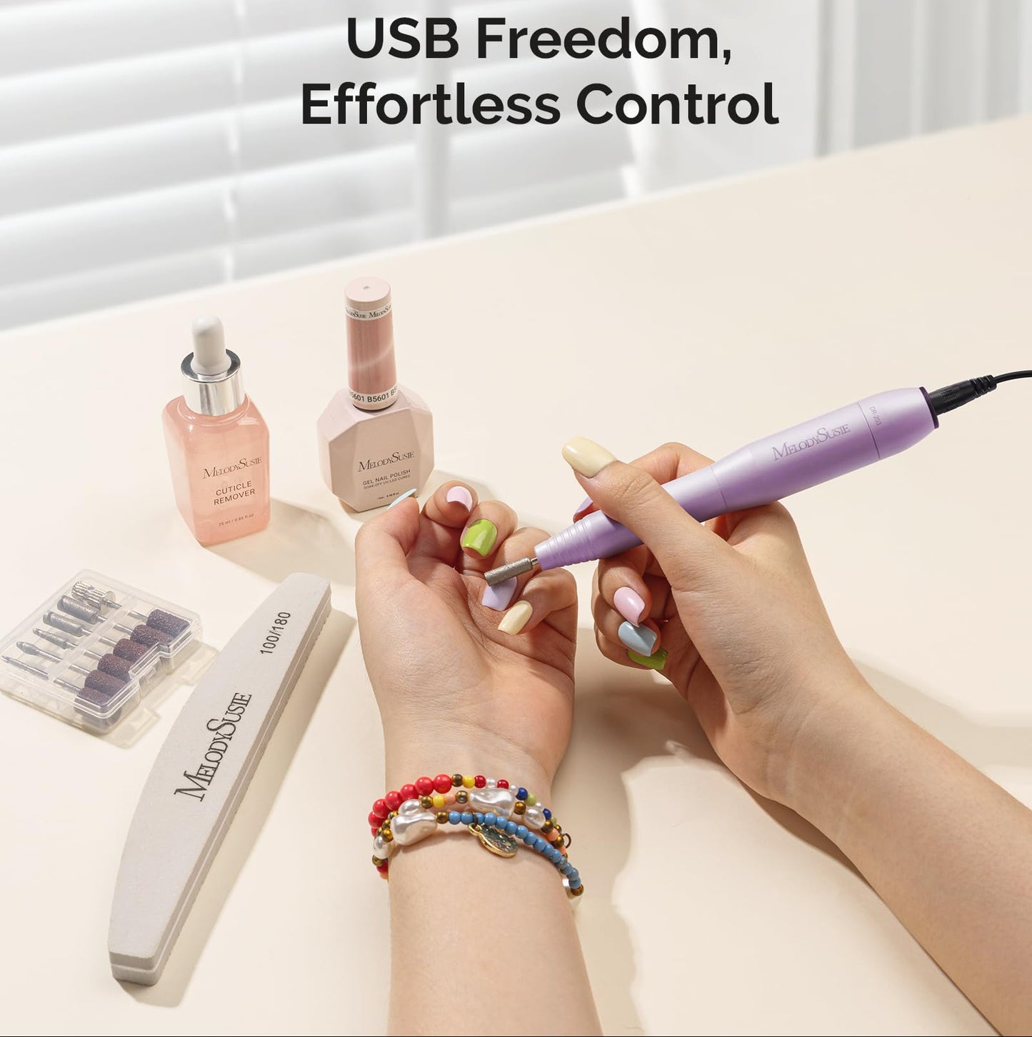 Person using a nail drill with Melodiusse products on a light surface.