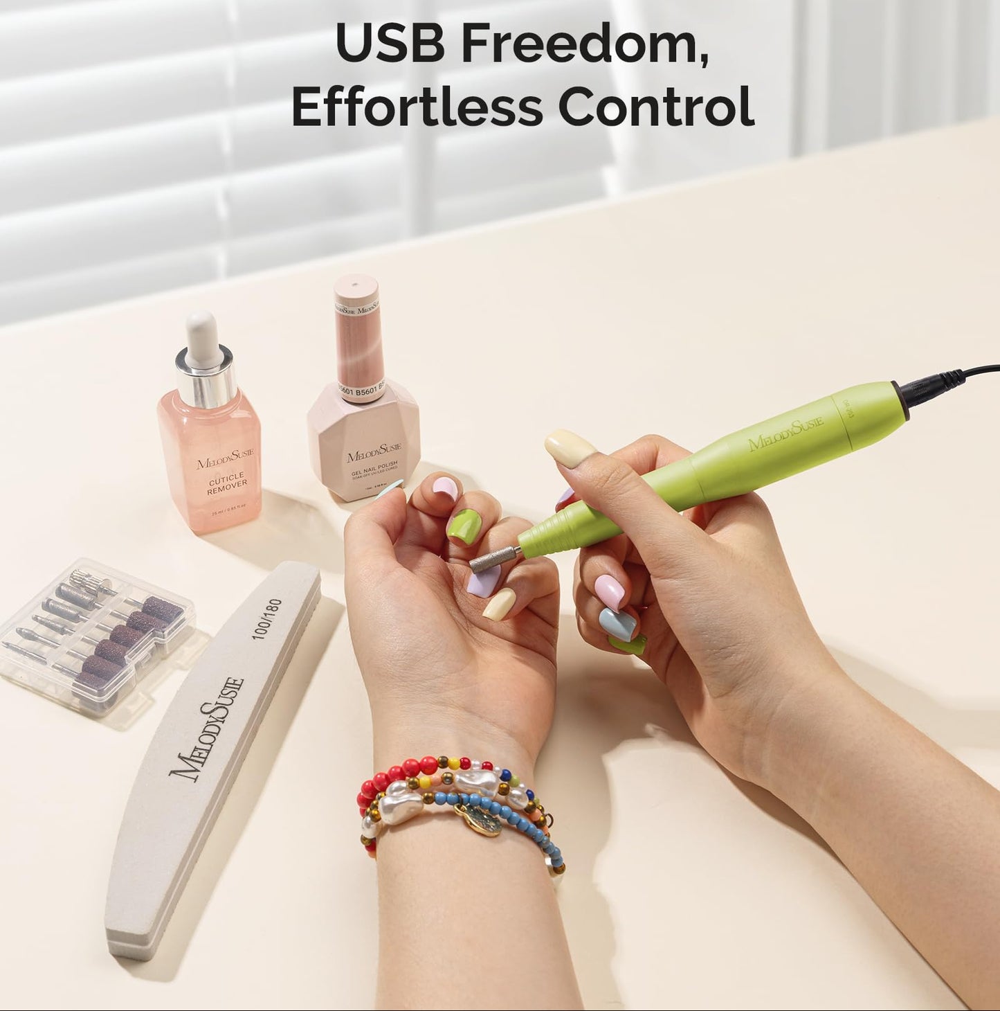 Person using a nail drill with Melodiusie products on a table.