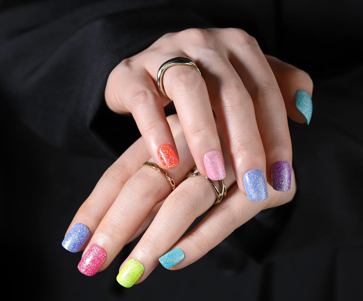 Hand with colorful nail polish and rings on a black background, featuring the brand 'Fandamei'.