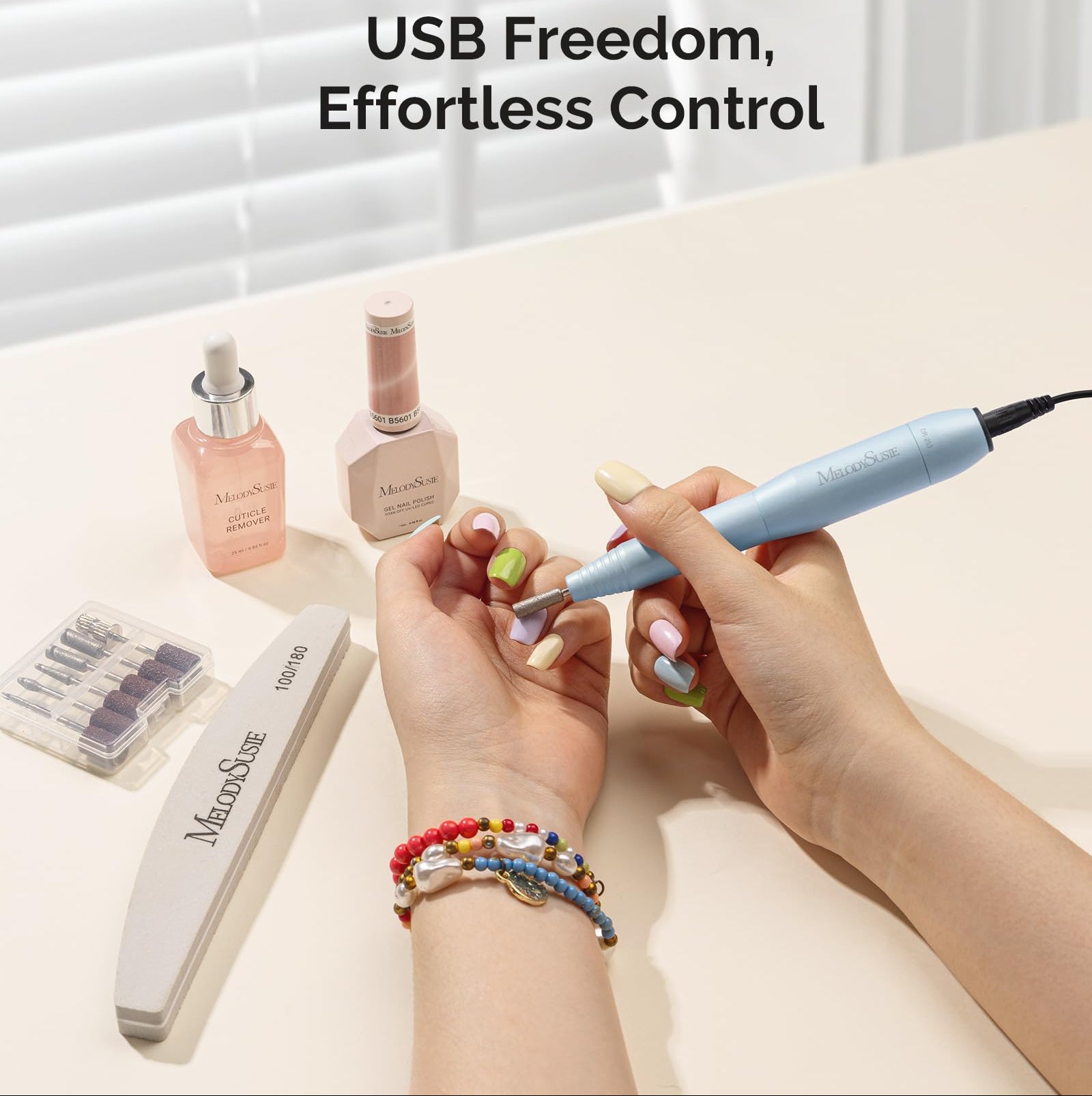 Person using a nail drill with Melodiusse products on a light surface.