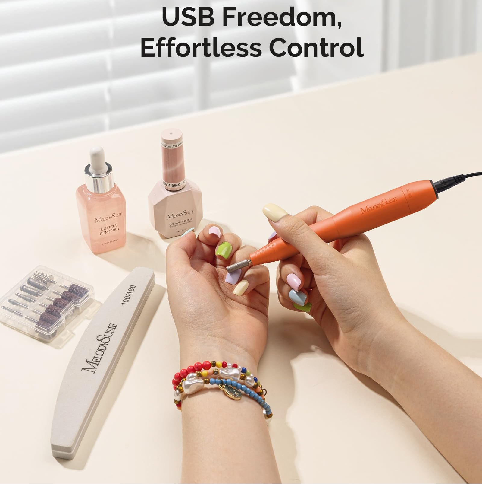 Person using a nail drill with Melodiusse products on a light surface.