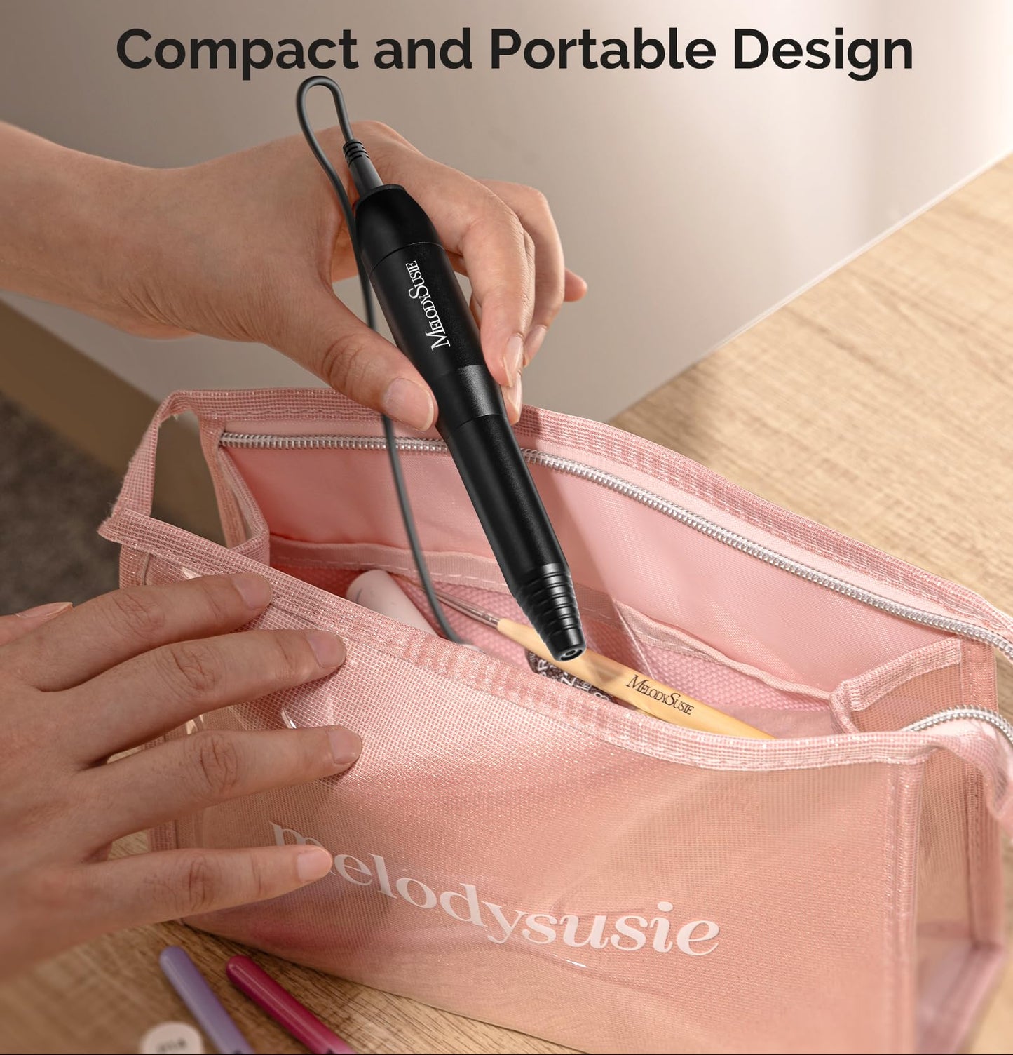 Compact nail drill held by a hand with a pink bag labeled MelodySusie in the background.
